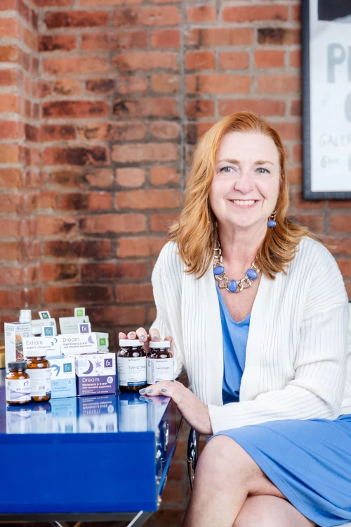 Georgia Austin with samples of supplements she recommends on table next to her.